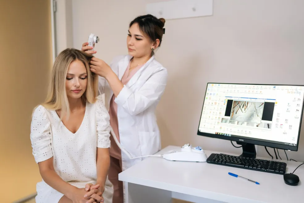 Tricholožka vyšetřuje ženě pokožku hlavy a vlasové kořínky v ambulanci