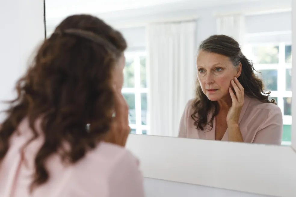 Žena si před zrcadlem kontroluje stav pleti během pravidelné skincare rutiny