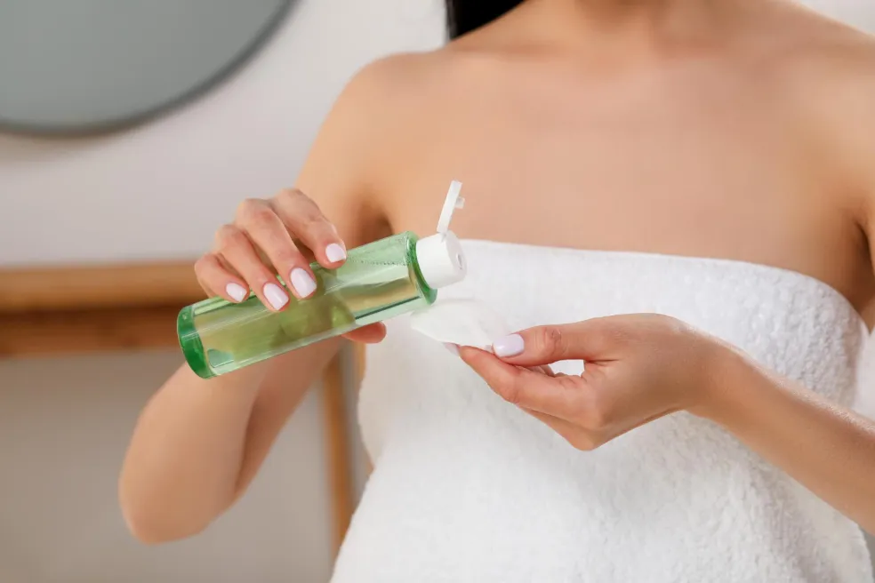 Žena si odličuje pleť micelární vodou pomocí vatového tamponku