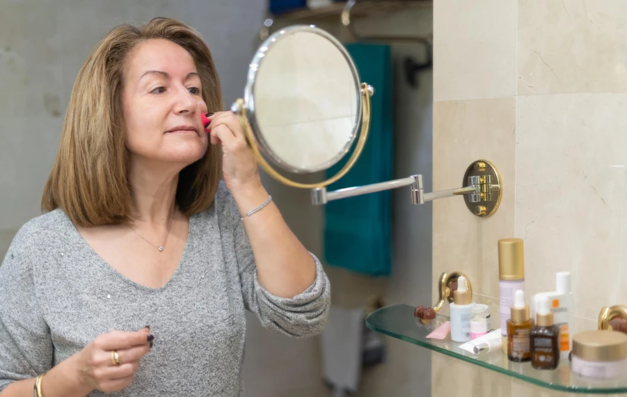 zralá žena při přirozeném líčení nanáší make-up na obličej